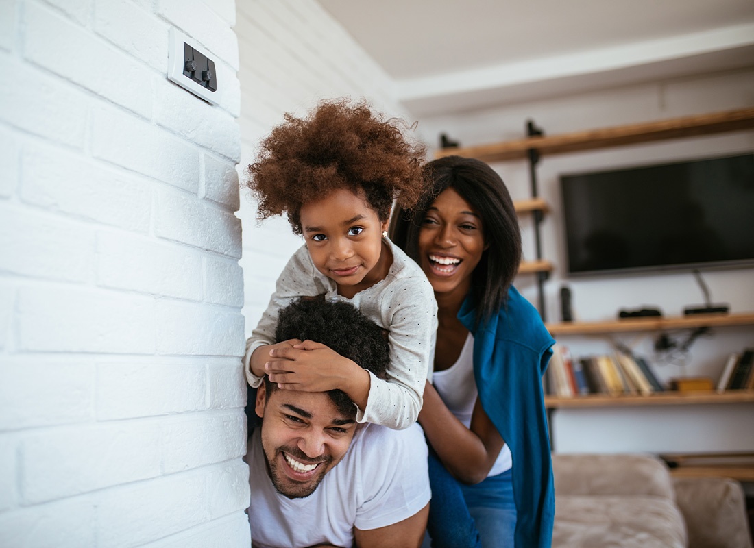 Personal Insurance - Happy Family Having Fun in New Home and Being Silly While Peeking Around the Corner of Their Living Room